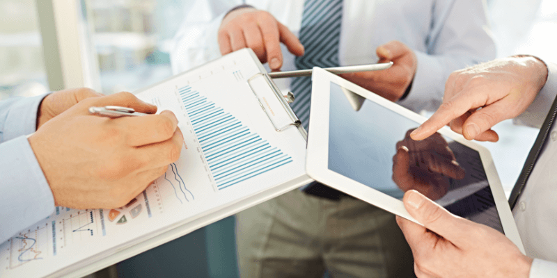 Three office workers compare data on three separate tablets