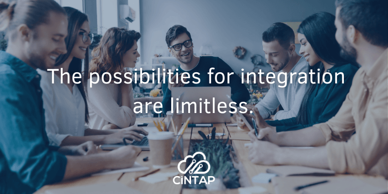 A business team collaborating at a shared desk. The text overlay reads, ”the possibilities for integration are limitless: CINTAP.”